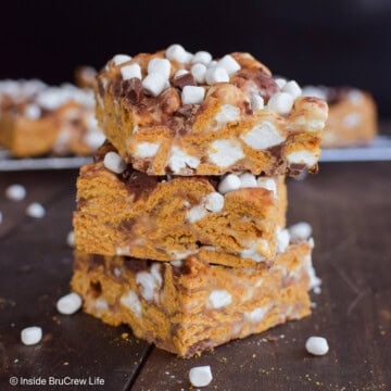 A stack of three golden graham s'mores bars on a wooden board.