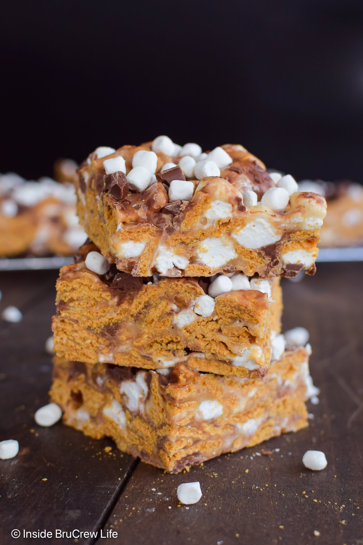 A stack of three golden graham s'mores bars on a wooden board.