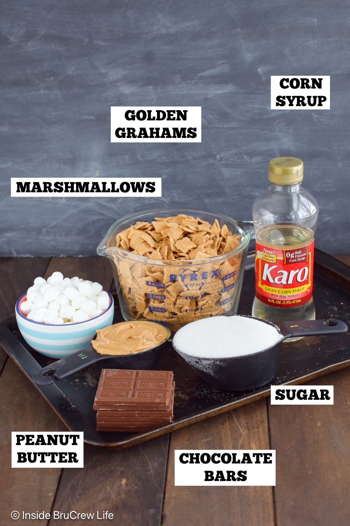Ingredients on a pan to make s'mores bars with golden grahams and peanut butter.