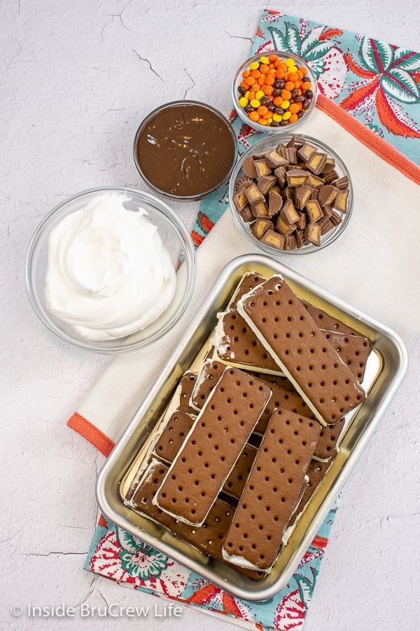 A white board with bowls of ingredients needed to make a peanut butter cup ice cream cake.