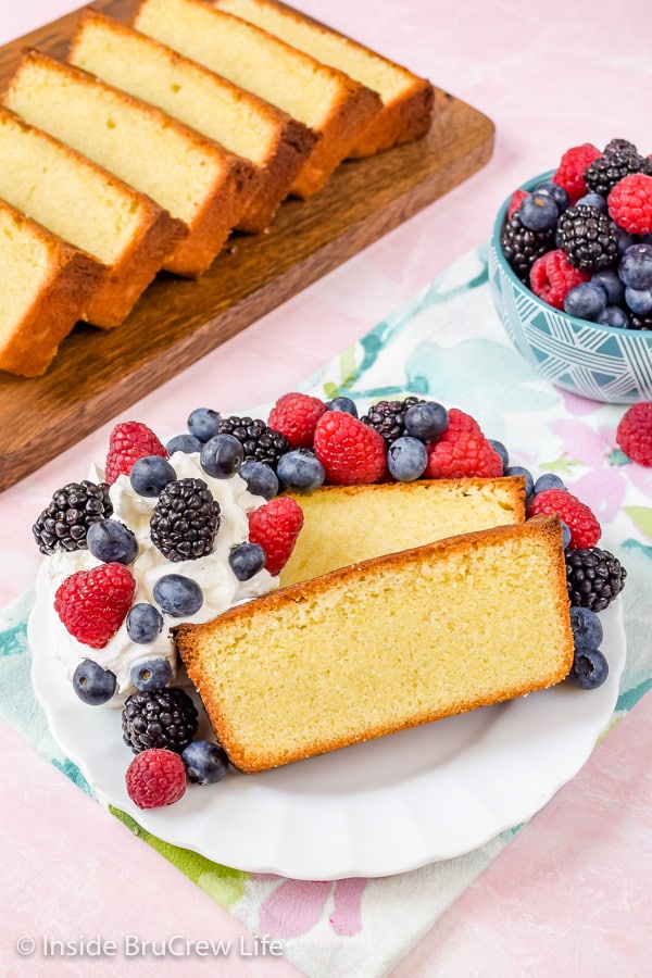 Overhead picture of a white plate with slices of vanilla cake, whipped cream, and berries on it.