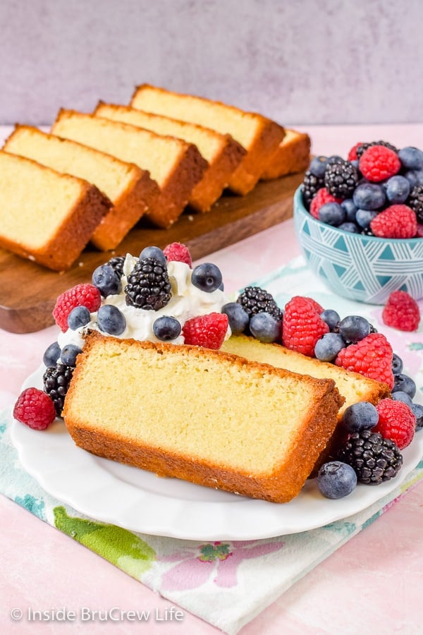 A plate with pound cake slices, fresh berries, and whipped cream on it.