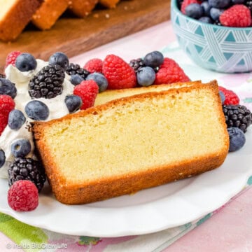 A white plate with vanilla pound cake slices, whipped cream, and berries on it.