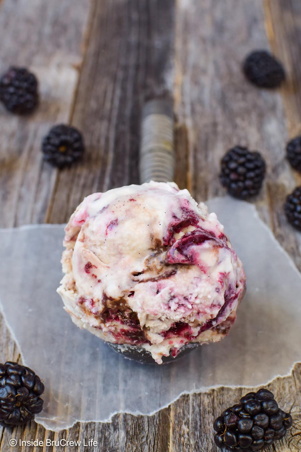 A scoop of fudge swirl ice cream with blackberry preserves in it.