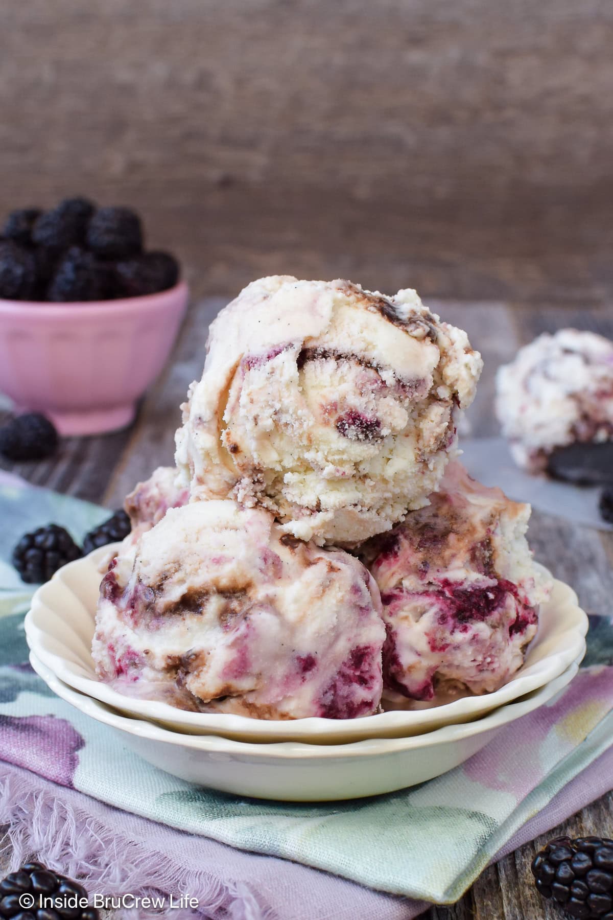 A bowl filled with three scoops of blackberry fudge swirl ice cream.