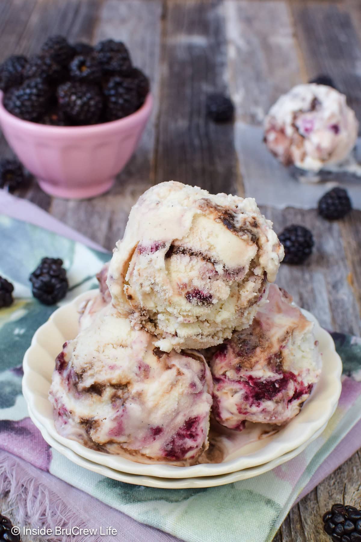 Scoops of vanilla fudge swirl ice cream in a white bowl.