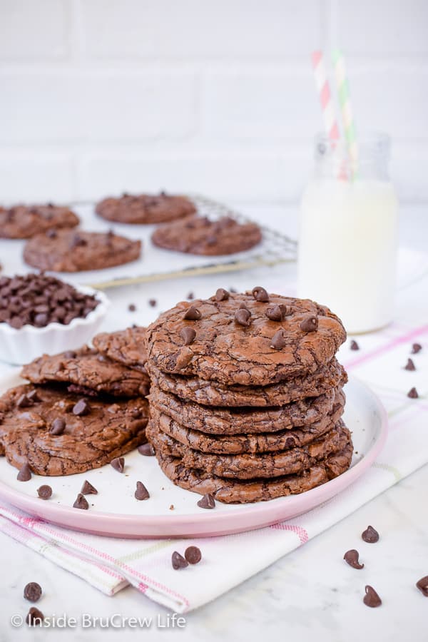 A pink and white plate with stacks of chocolate brownie cookies on it.