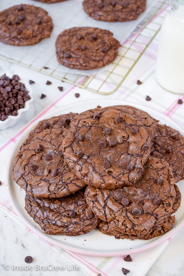 Overhead picture of a pink and white plate with lots of chewy brownie cookies stacked on it.