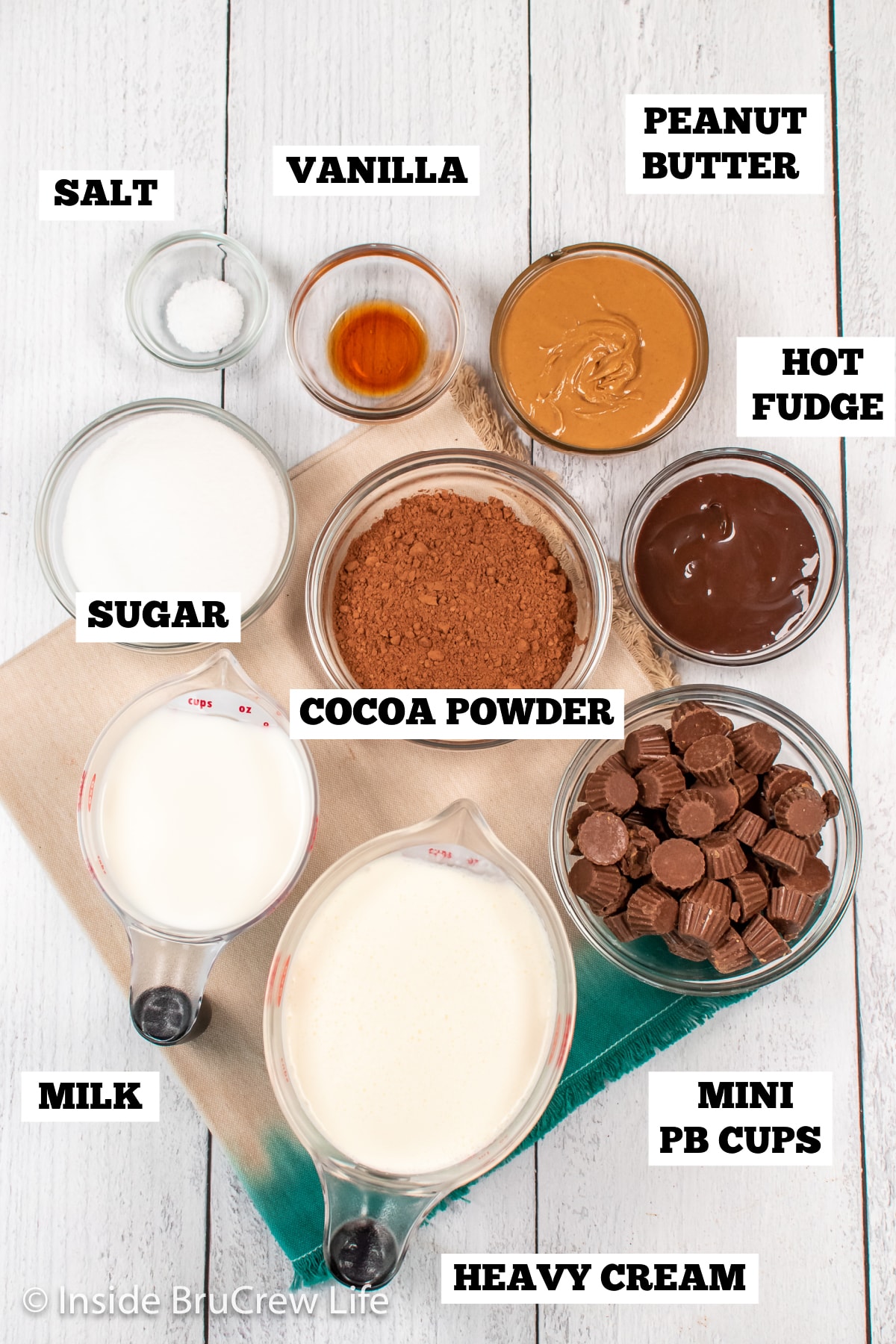 A white board with bowls of ingredients needed to make chocolate ice cream with peanut butter cups.