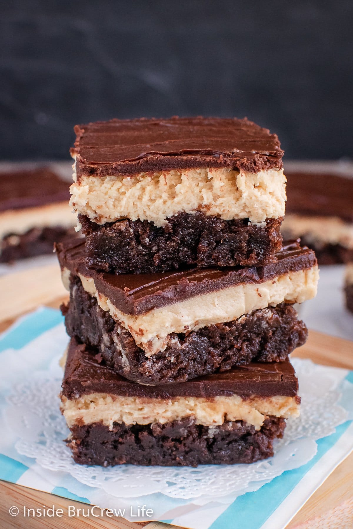 Three chocolate brownies with peanut butter filling stacked on a paper.