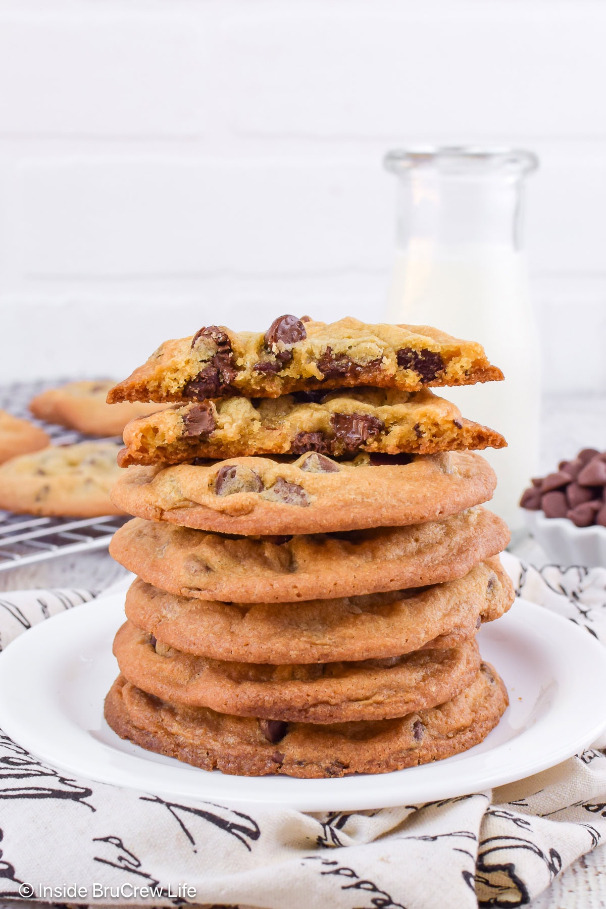 Chocolate chip cookies stacked on a white plate.