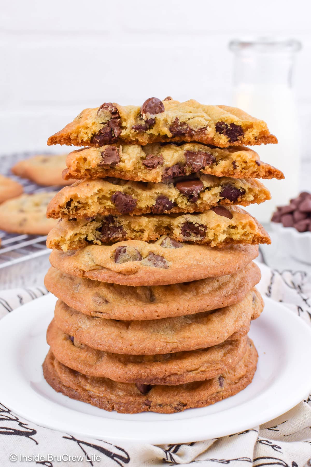 A large stack of crispy chocolate chip cookies on a white plate.