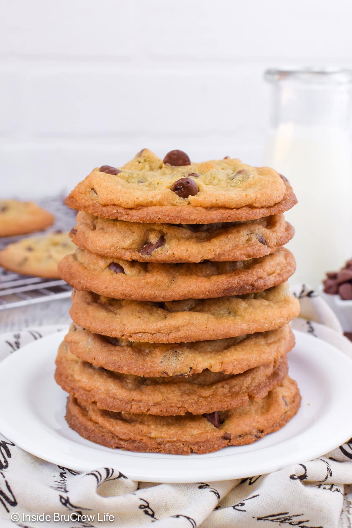 A tall stack of crispy and chewy chocolate chip cookies on a plate.
