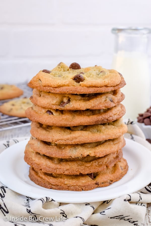 A white plate with a stack of chocolate chip cookies on it.