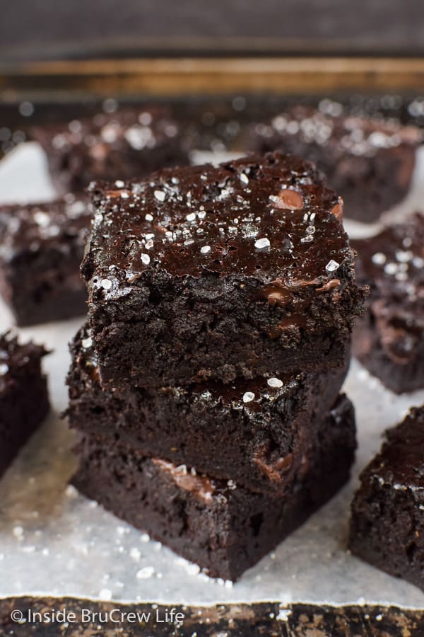 Three chocolate zucchini brownies stacked together with more brownies all around it