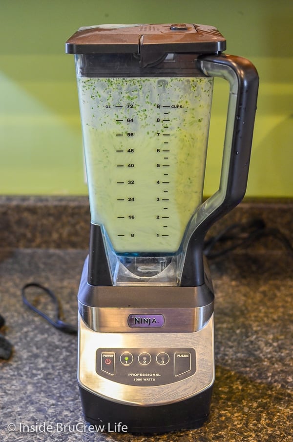 A blender filled with a green sauce for chicken enchiladas.