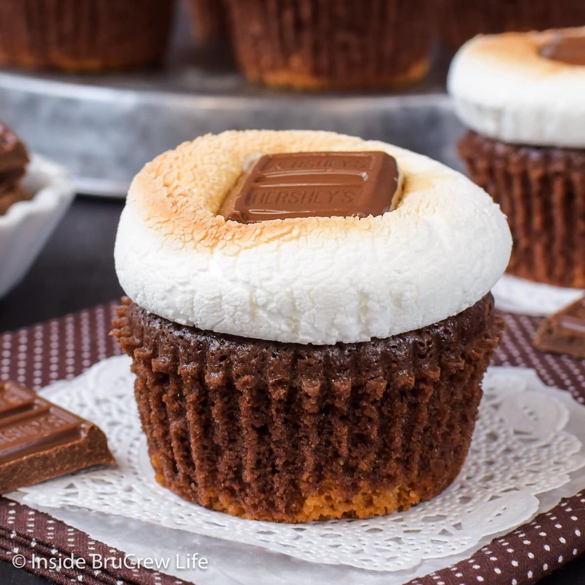 A chocolate cupcake topped with toasted marshmallow and a candy bar.