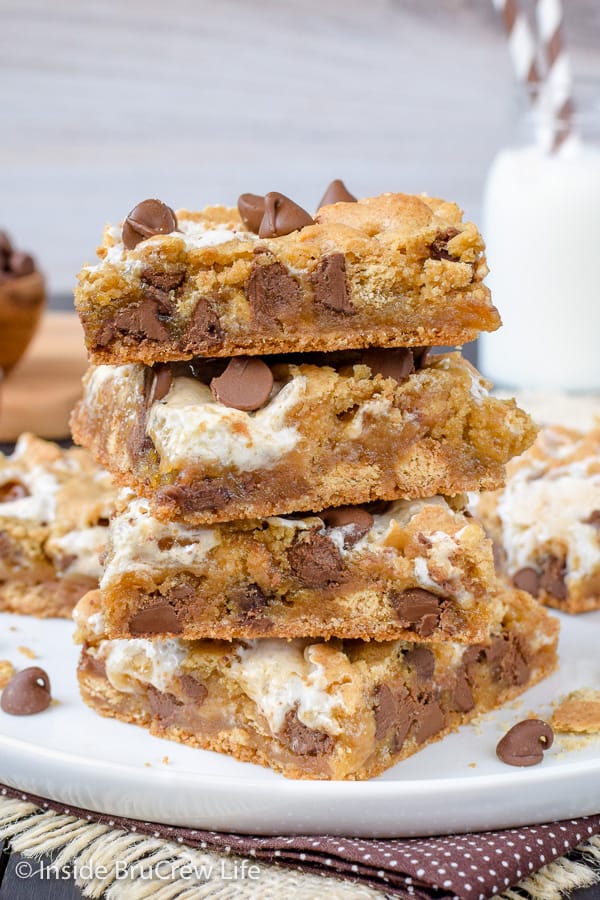 Four s'mores blonde brownies stacked on a white plate.