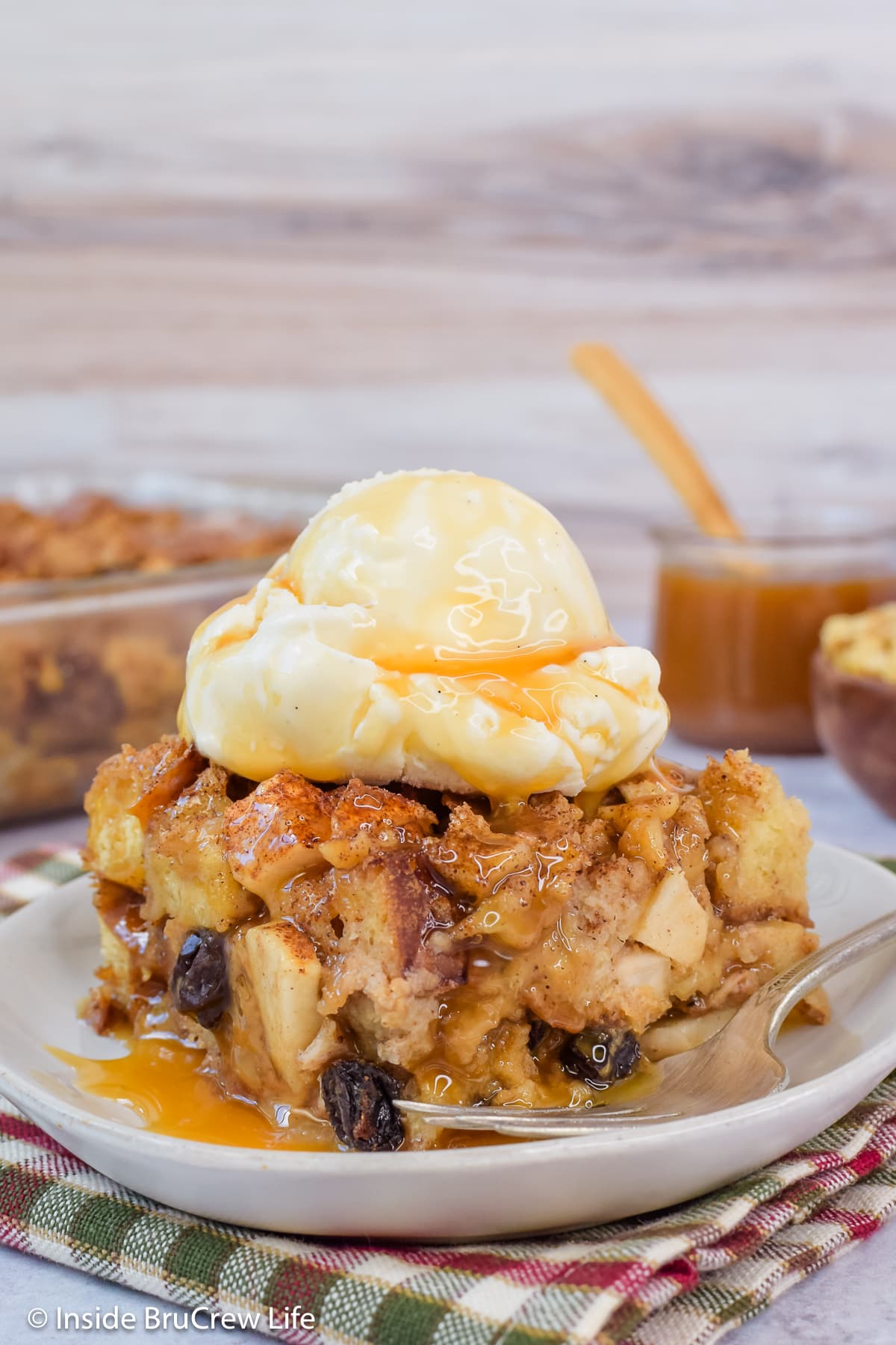 A square of apple dessert casserole topped with ice cream and caramel.