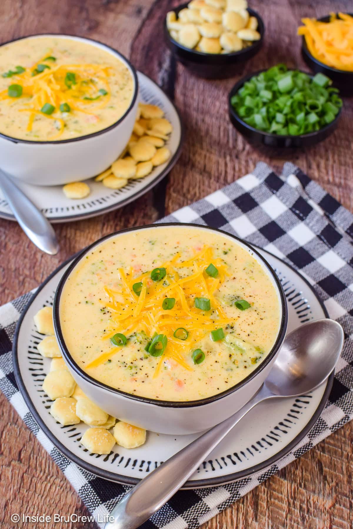 Two bowls of cheese soup loaded with broccoli chunks.