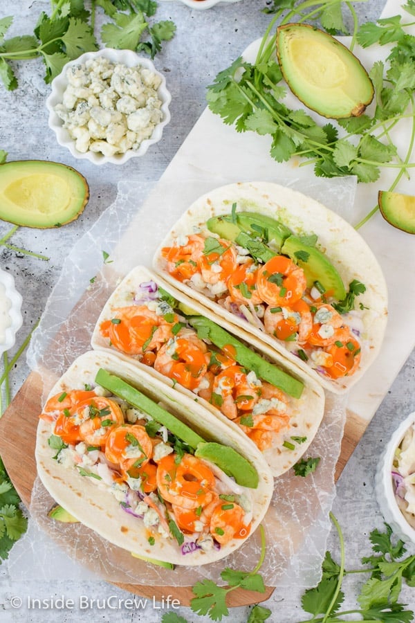 Easy Buffalo Shrimp Tacos - lots of toppings and buffalo shrimp make these easy shrimp tacos a win at the dinner table. Make this easy recipe on busy nights! #tacos #buffaloshrimp #shrimptacos #tacotuesday