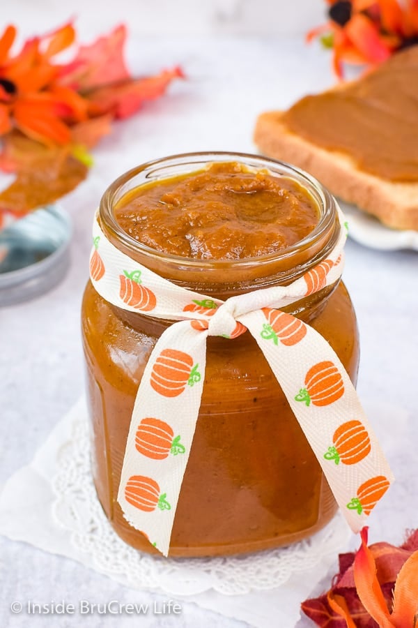 A clear jar with a ribbon filled with homemade pumpkin butter.