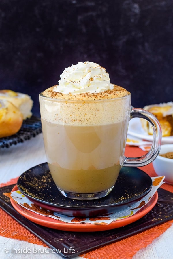 A black plate with a clear mug filled with a sugar free pumpkin spice latte made with soy milk.