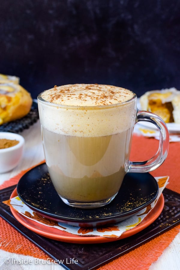 A black plate with a clear mug filled with a pumpkin spice latte made with sugar free syrup and soy milk.