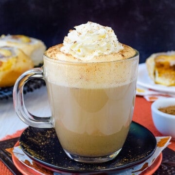 A clear mug with pumpkin spice latte in it.