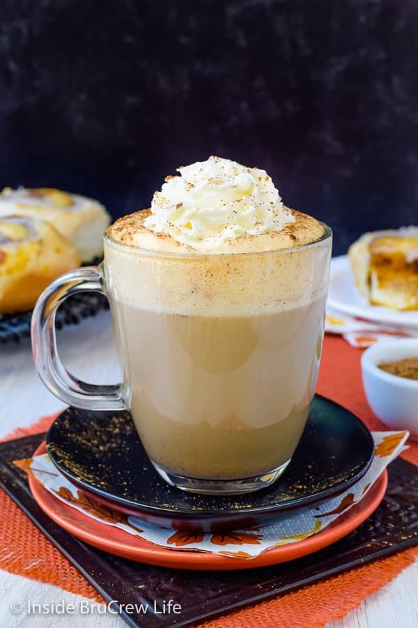 A clear mug filled with a sugar free pumpkin spice latte topped with whipped cream and pumpkin spice.