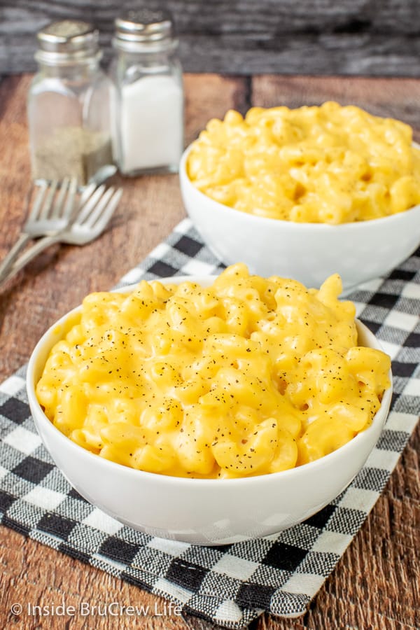 Two white bowls on a black and white towel filled with the creamiest homemade mac and cheese