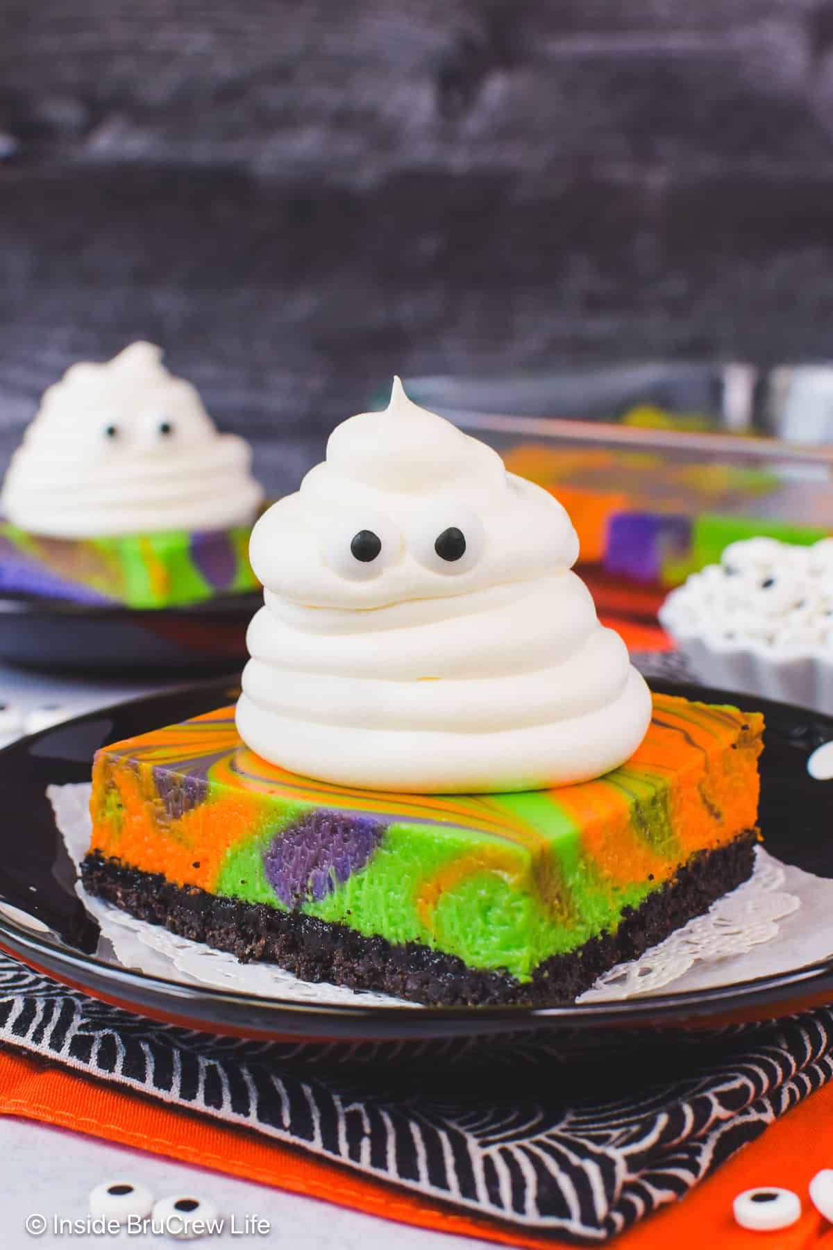 A close up of a whipped cream ghost on a swirled halloween cheesecake bar.