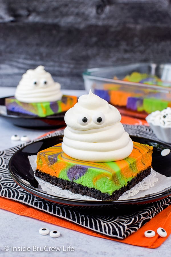 Black plates with marbled cheesecake bars topped with Cool Whip ghosts.