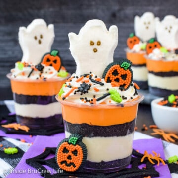 Clear cups filled with layers of vanilla cheesecake and Oreo cookie crumbs and topped with a ghost peep.