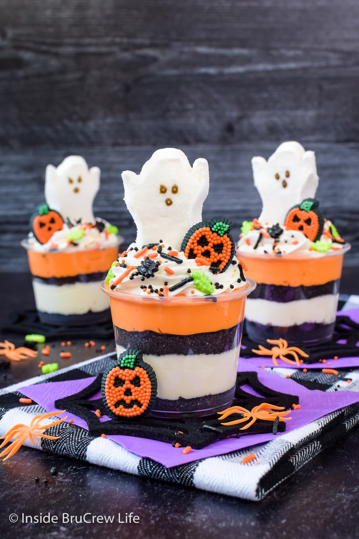 Three Halloween cheesecake cups with marshmallow ghosts on top.