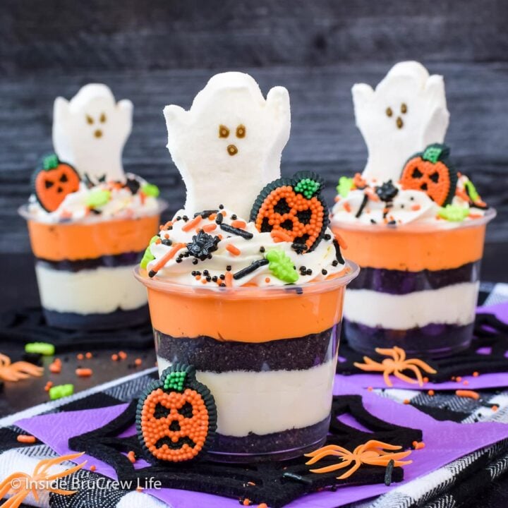 Three Halloween cheesecake cups with marshmallow ghosts on top.