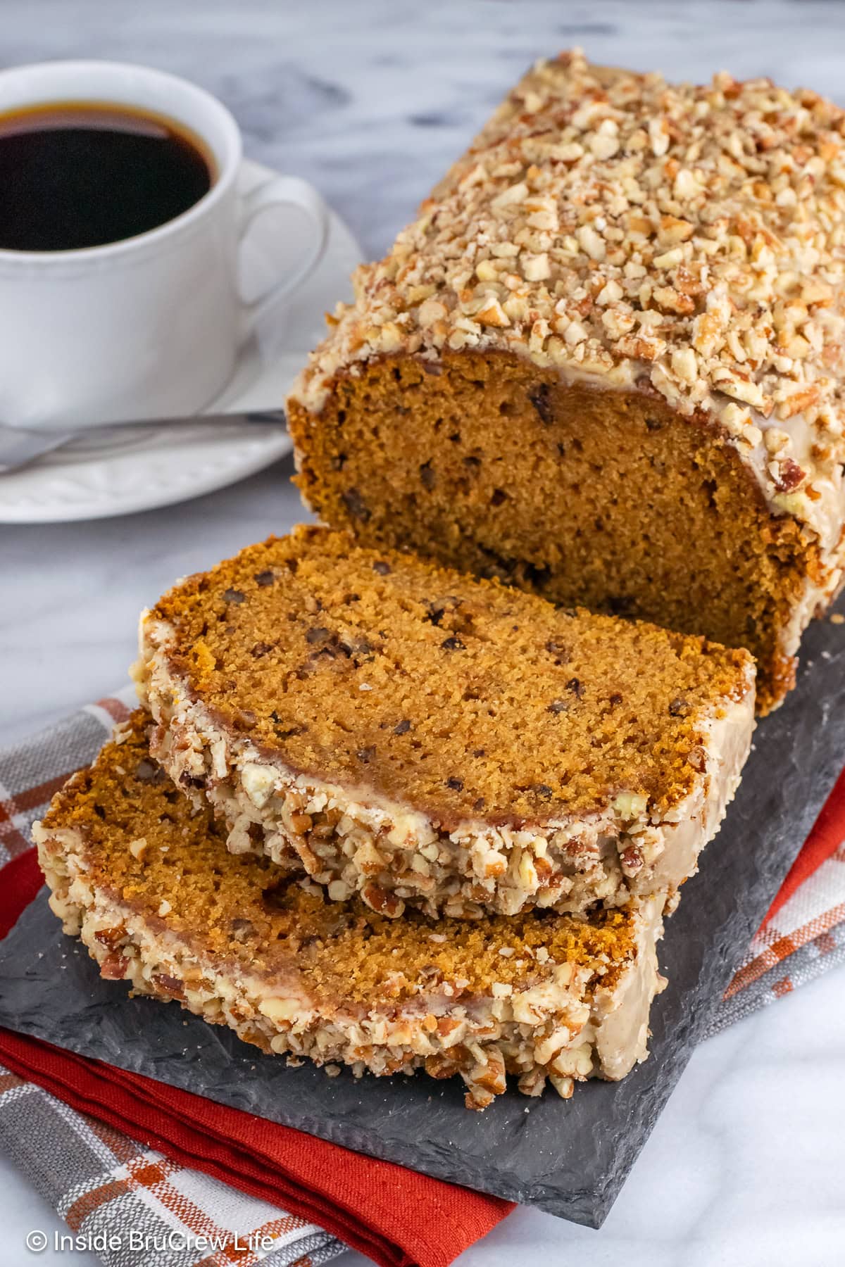 A loaf of pumpkin pecan bread on a slate tray.