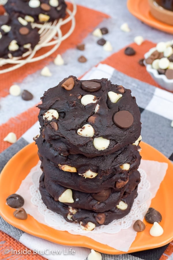 An orange plate with a stack of chocolate chip pumpkin cookies on it.