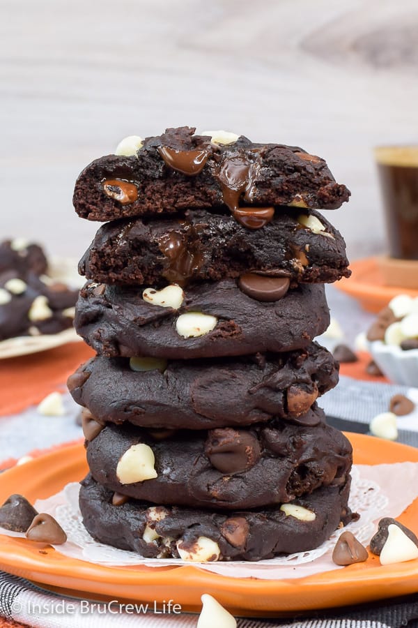 A stack of dark chocolate pumpkin cookies on an orange plate.