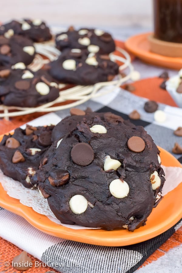 An orange plate with chocolate chip chocolate pumpkin cookies on it.