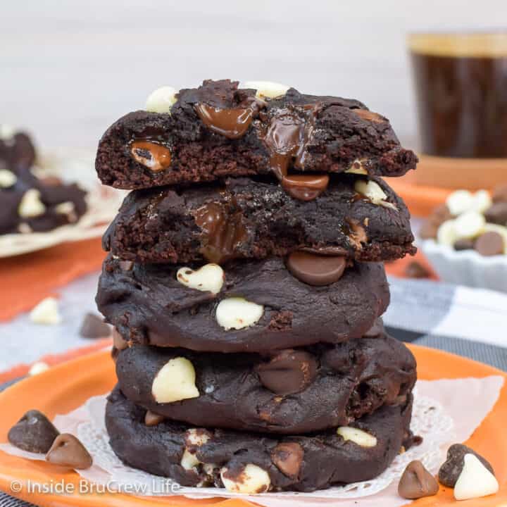 A stack of dark chocolate pumpkin cookies on an orange plate.