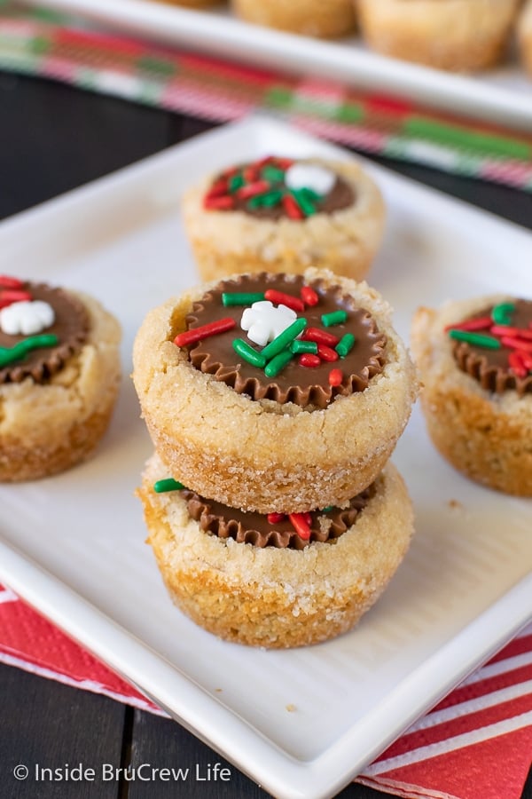 A white plate with five peanut butter cup cookies topped with holiday sprinkles on it.