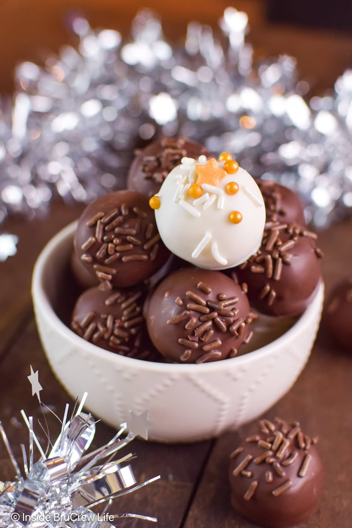 A white bowl filled with chocolate covered peanut butter balls.