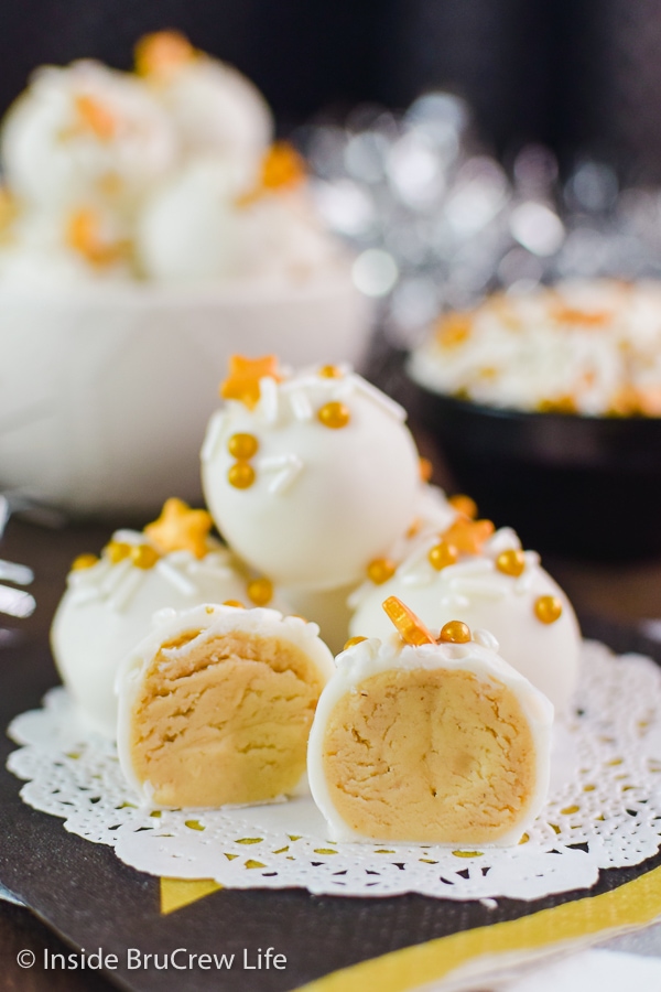 White chocolate peanut butter balls with  sprinkles stacked on a white doily.