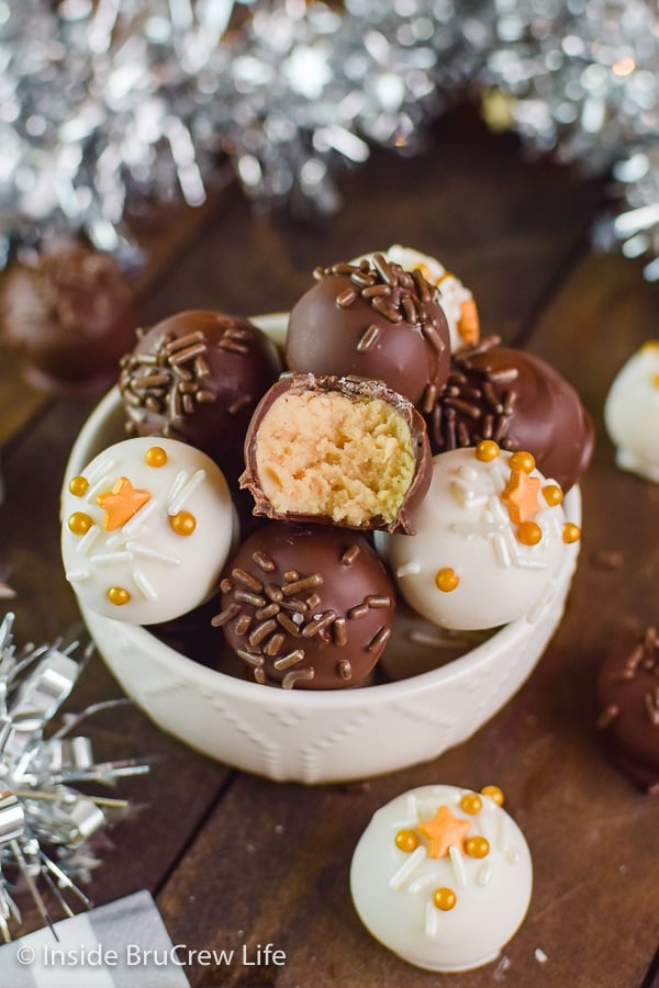 Overhead picture of a white bowl filled with peanut butter balls dipped in dark and white chocolate and topped with sprinkles.