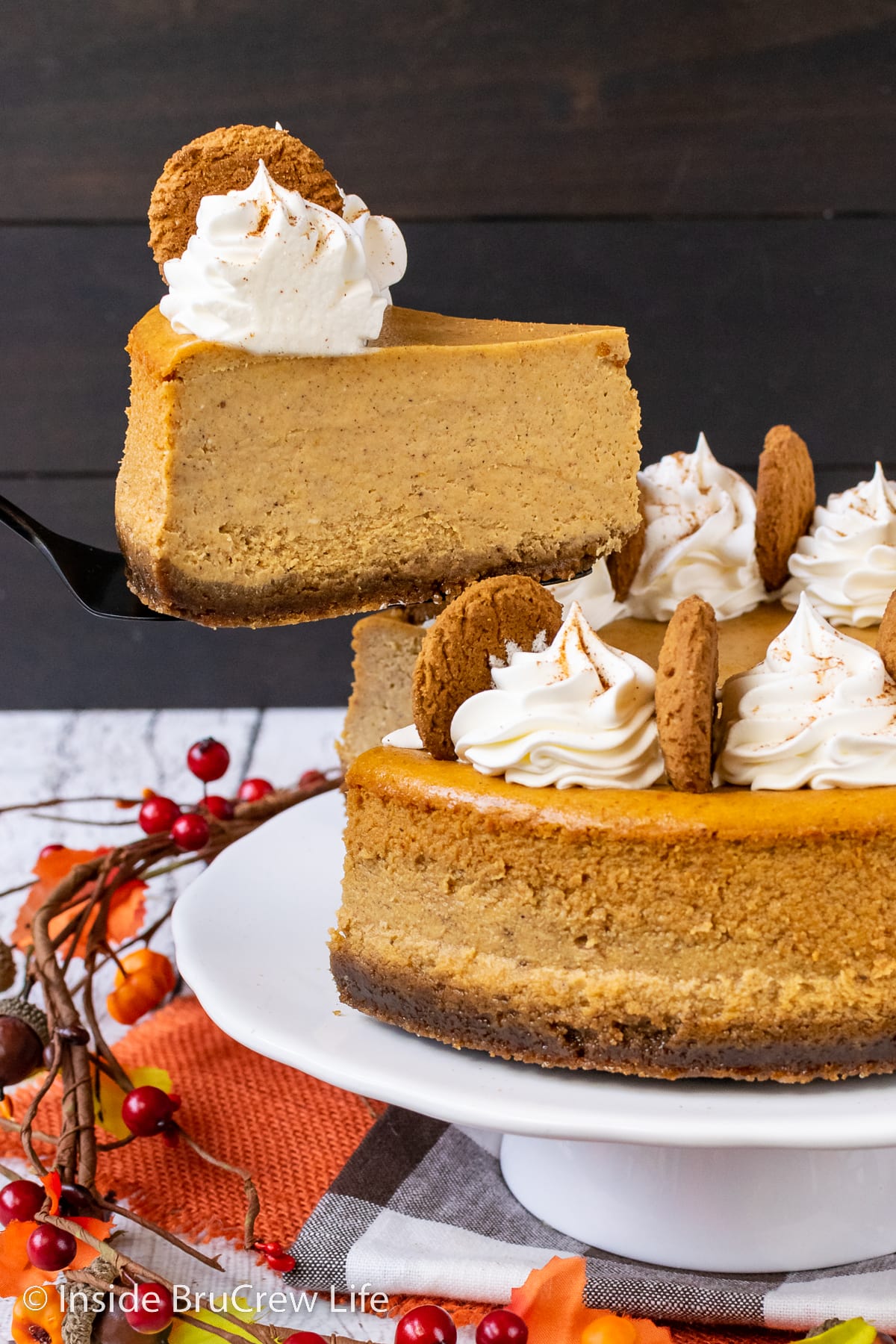 A spatula lifting a cheesecake off a cake stand.