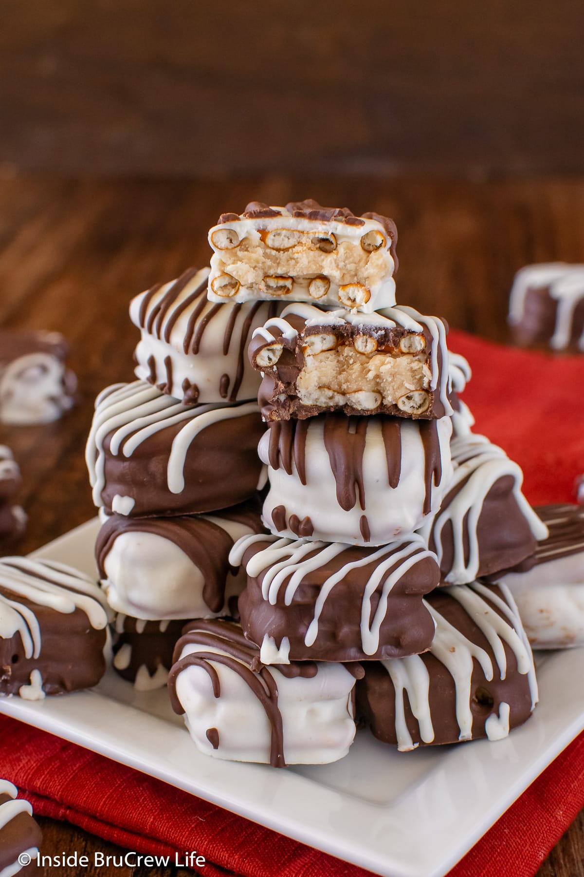 A stack of pretzels with peanut butter and chocolate on a white plate.