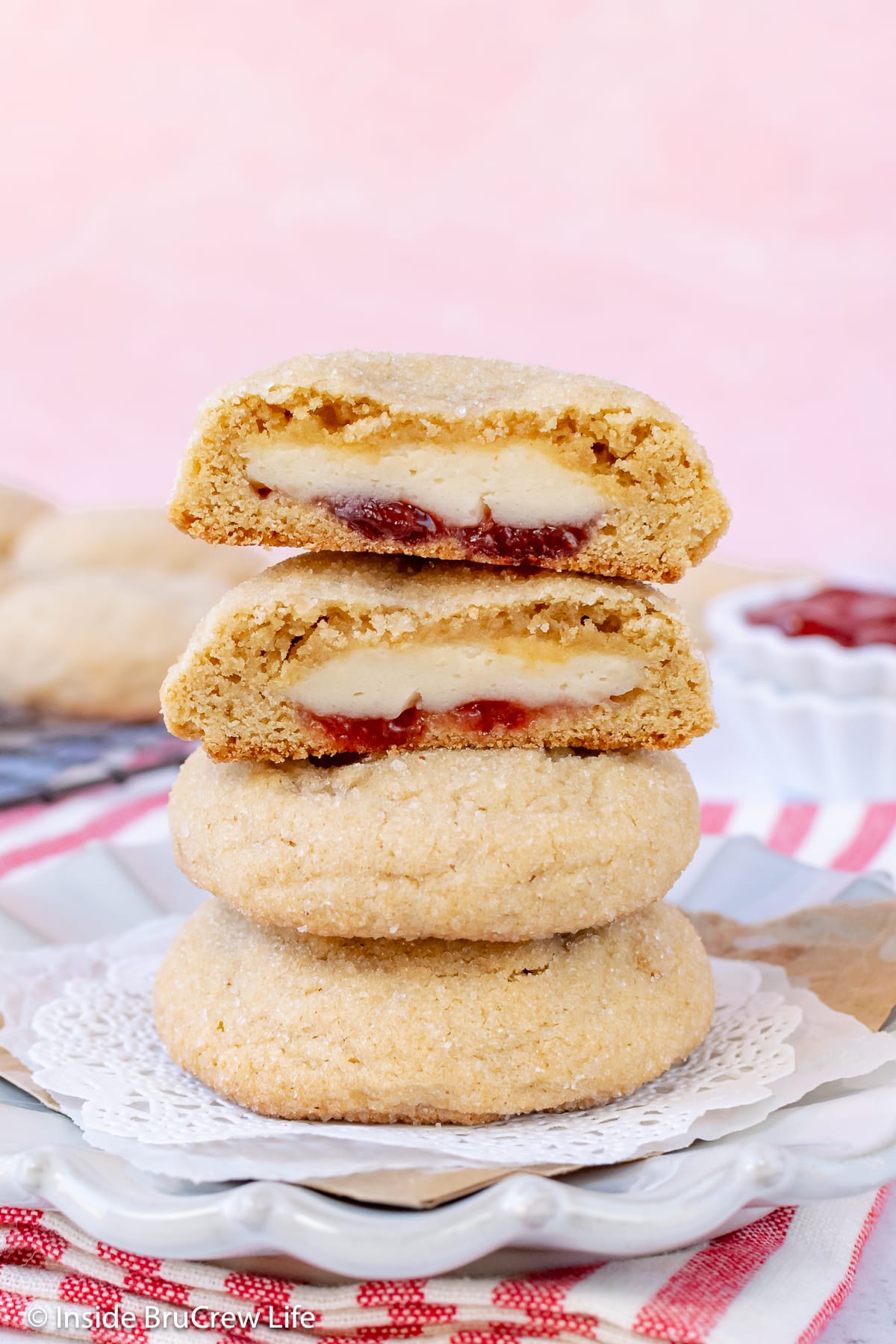 A stack of cheesecake filled cookies with one cut open.