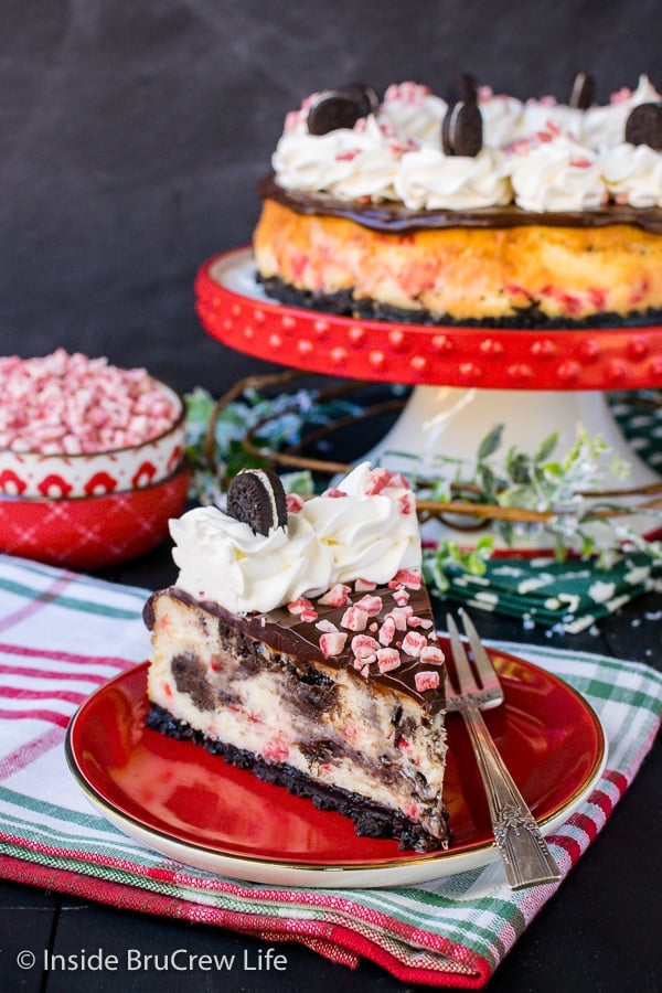 A slice of Peppermint Oreo Swirl Cheesecake with the full cheesecake in the background.