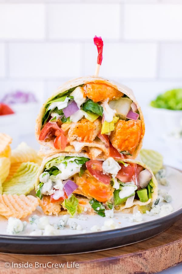 A buffalo wrap cut in half and stacked on top of each other showing all the veggies and cheese inside.
